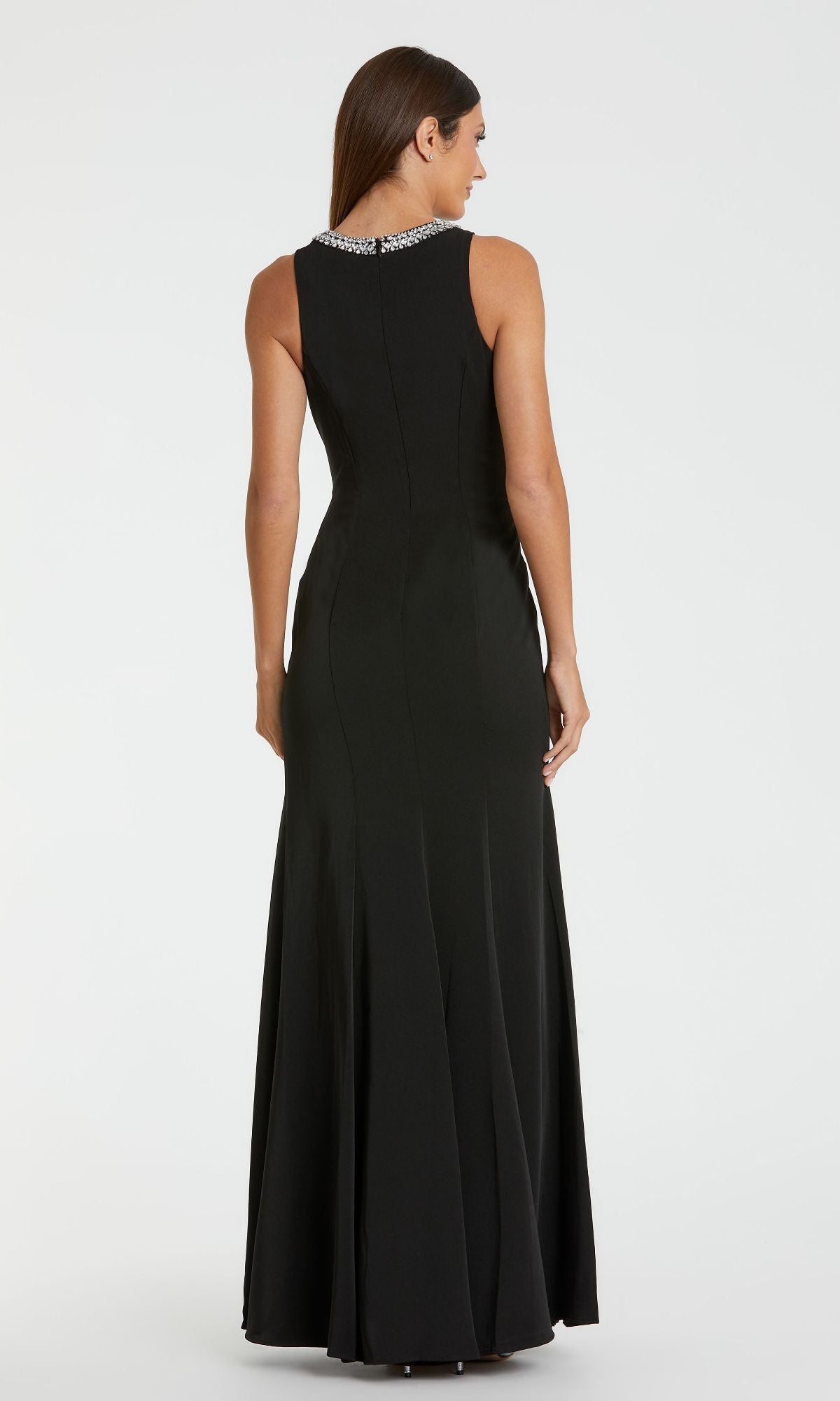 A woman stands facing away against a plain white background, wearing the Mac Duggal 49093 Beaded-Neck Long Prom Dress—a sleeveless gown with a fitted waist and silver beaded embellishments on the collar.